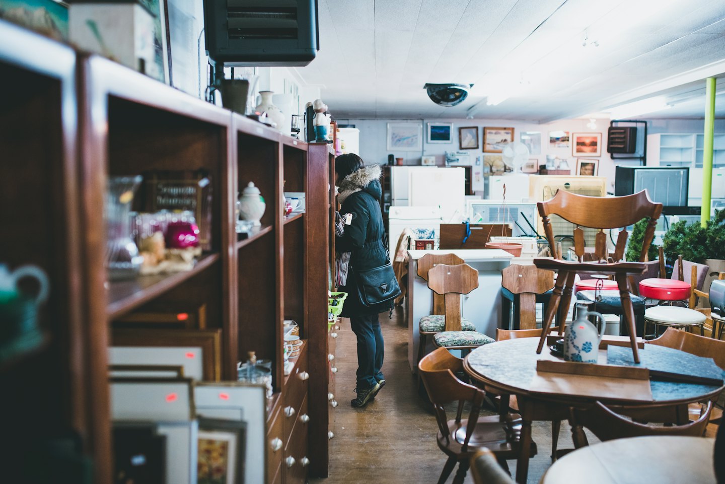 Kund tittar på varor i en hylla i en livlig secondhandbutik.