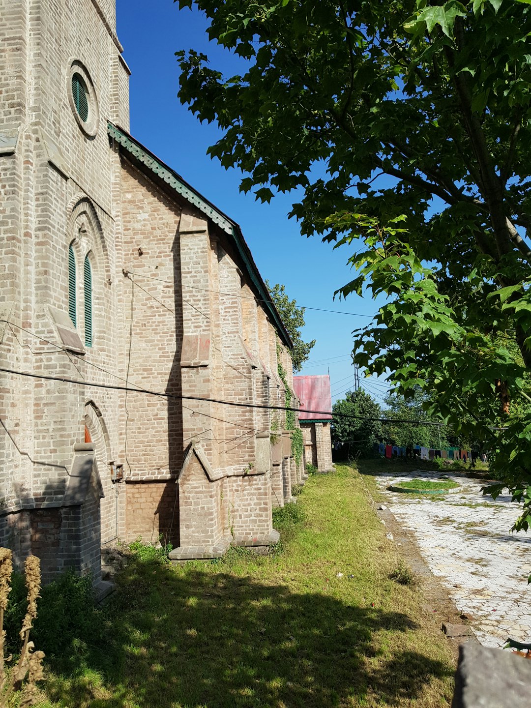 Gammal tegelkyrka med gröna fönsterluckor och välvda fönster.